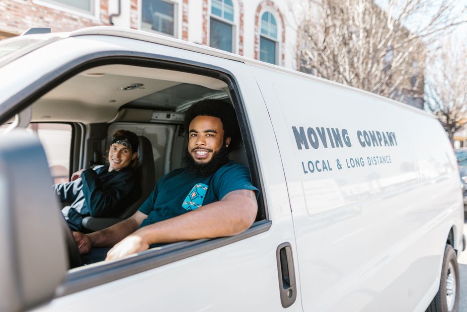 Friendly and professional movers smiling while carrying boxes